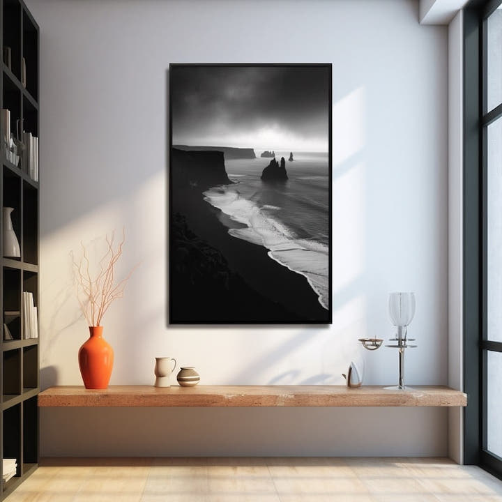 Black and white seascape of volcanic cliffs and sea stacks above a black-sand shore