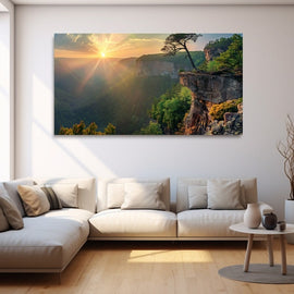 Panoramic sunrise bursting over a forested gorge with a windswept pine on a rocky outcrop