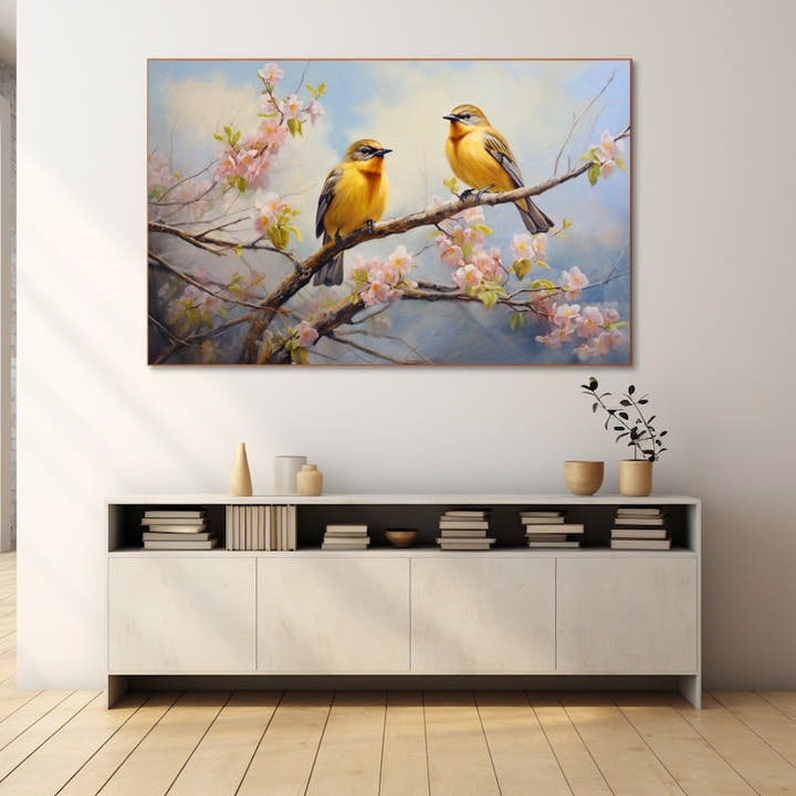 Two golden songbirds on a branch of pink spring blossom under a blue sky